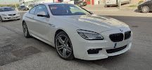 Un BMW Serie 6 Coupé blanco está estacionado al costado de la carretera.