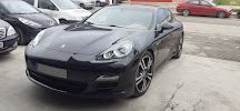 Un coche negro está estacionado en un estacionamiento al lado de otros coches.