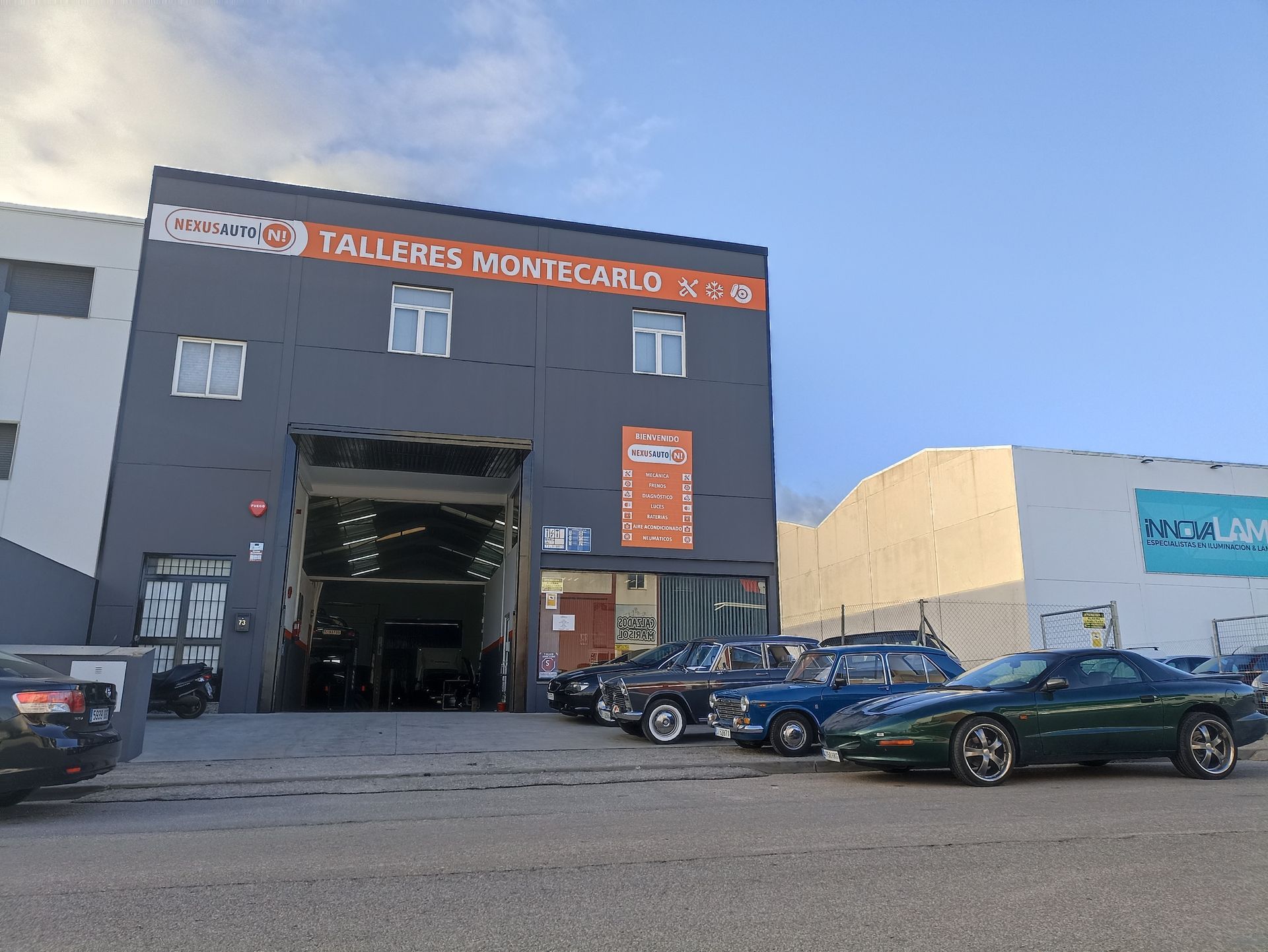 Una fila de autos están estacionados frente a un edificio que dice talleres