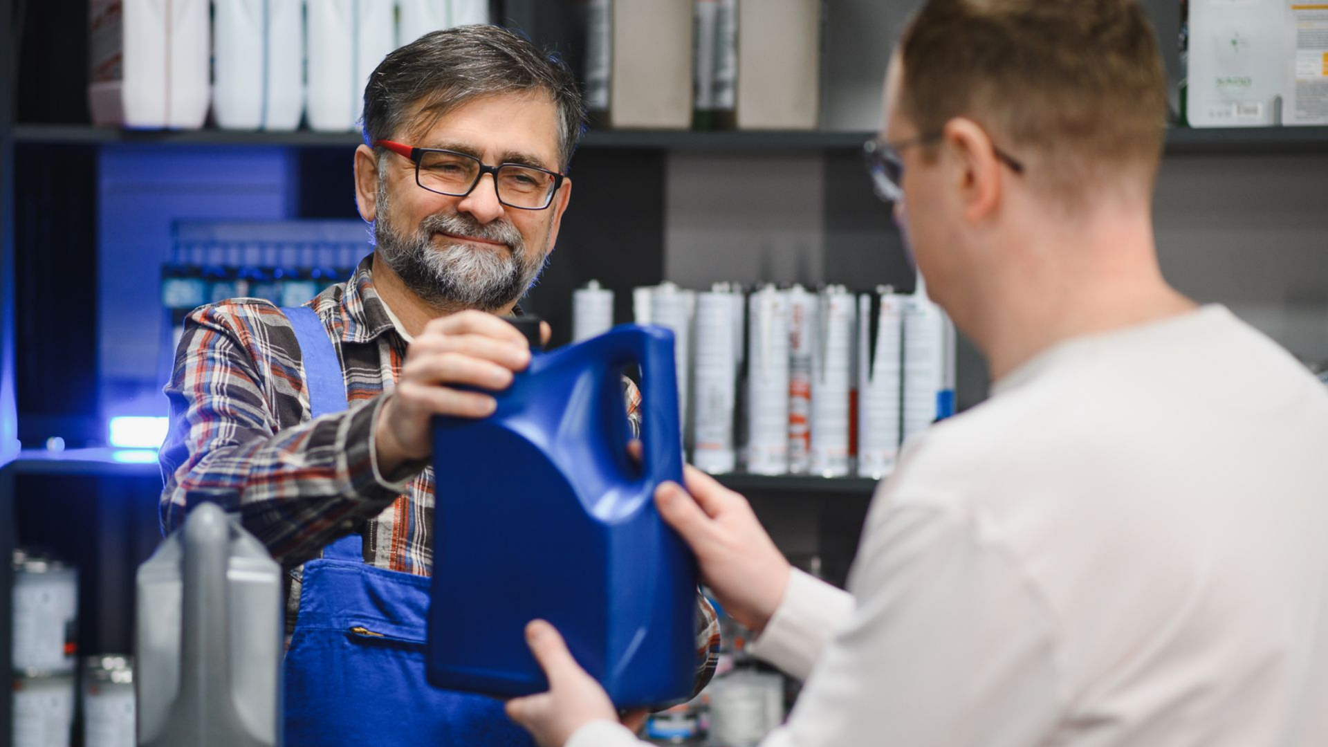 Un mécanicien remet un bidon bleu à un client dans un magasin.
