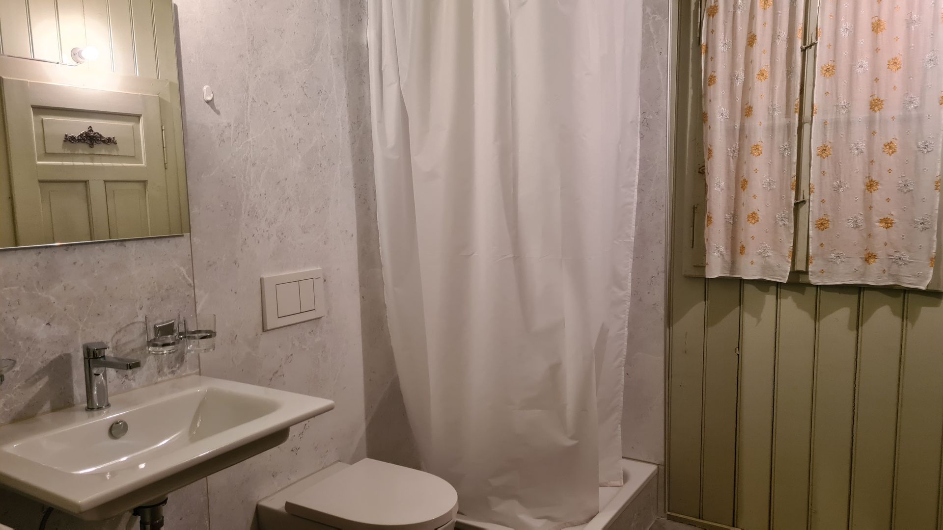 Ein WC und eine Dusche mit weissem Duschvorhang.