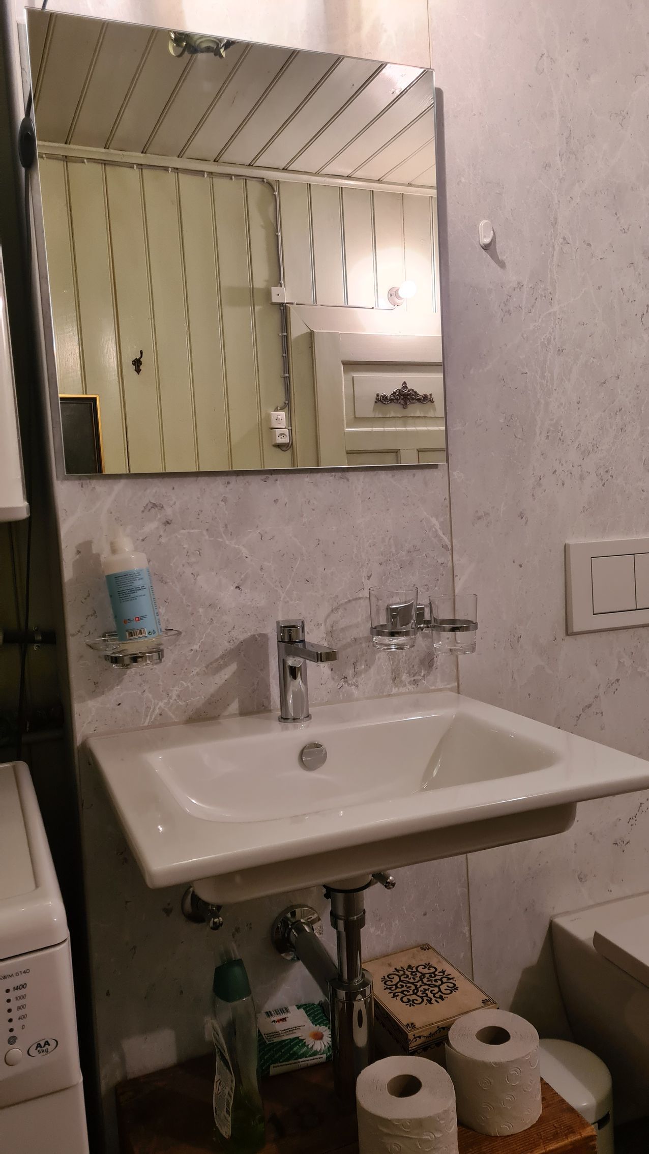 Ein Lavabo, darüber ein Spiegel an der Wand.