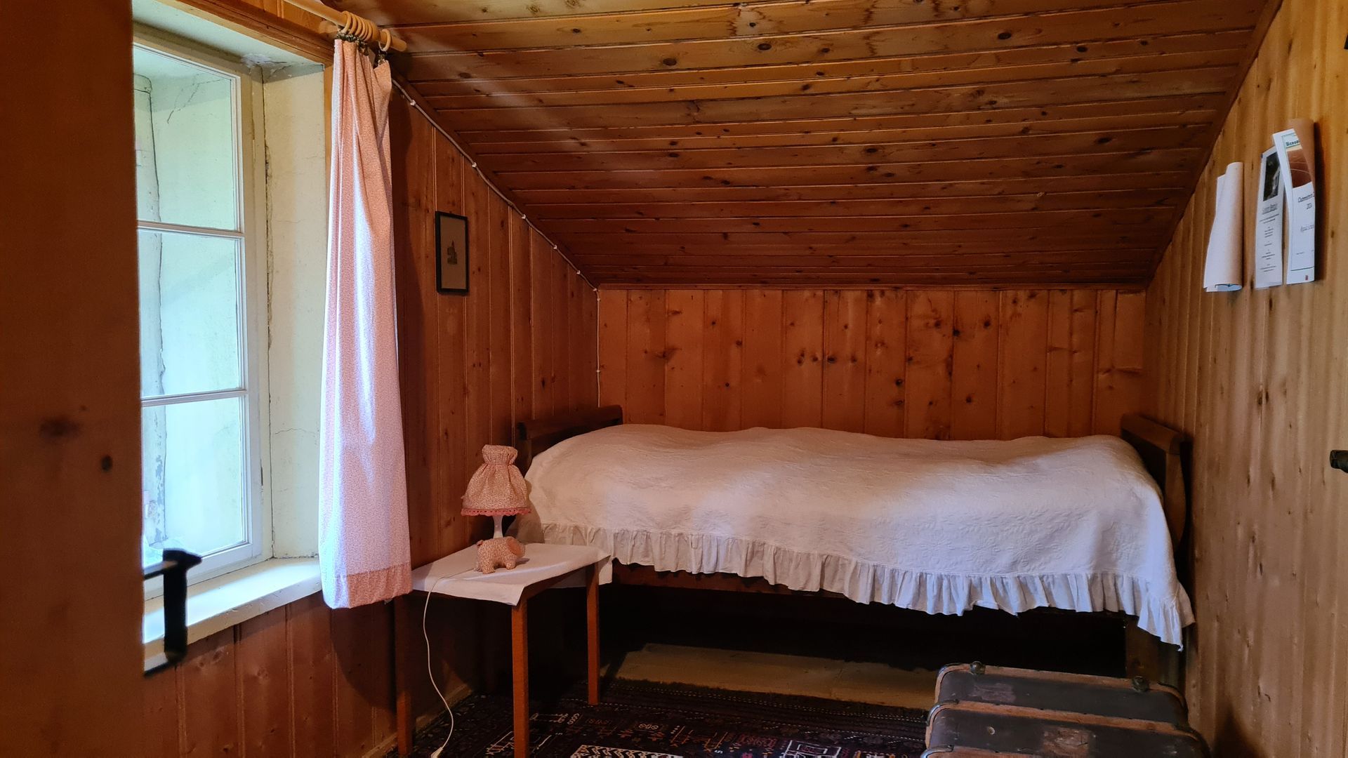 Ein kleines Schlafzimmer mit Täferwänden und einer rosa Nachttischlampe.