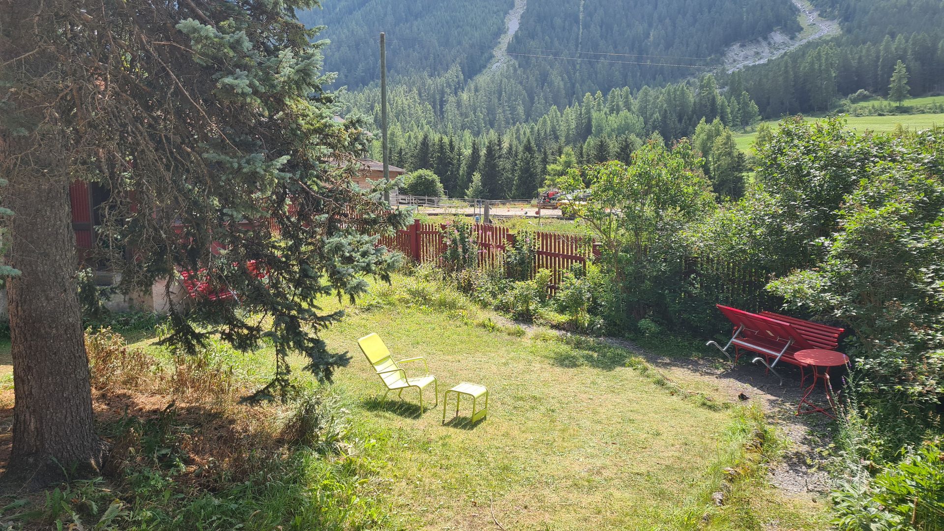 Ein blassgrüner Gartensessel mit Fussbank steht auf einer Wiese in der Sonne.