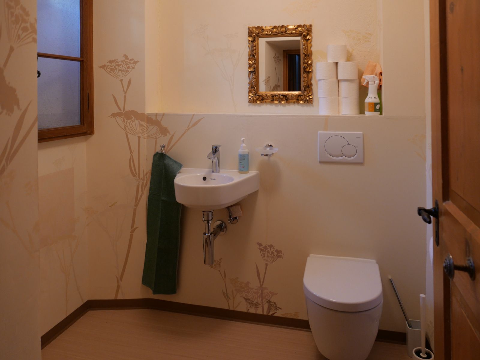 Ein kleiner Raum mit WC und Lavabo, an der Wand Schablonenmalereien