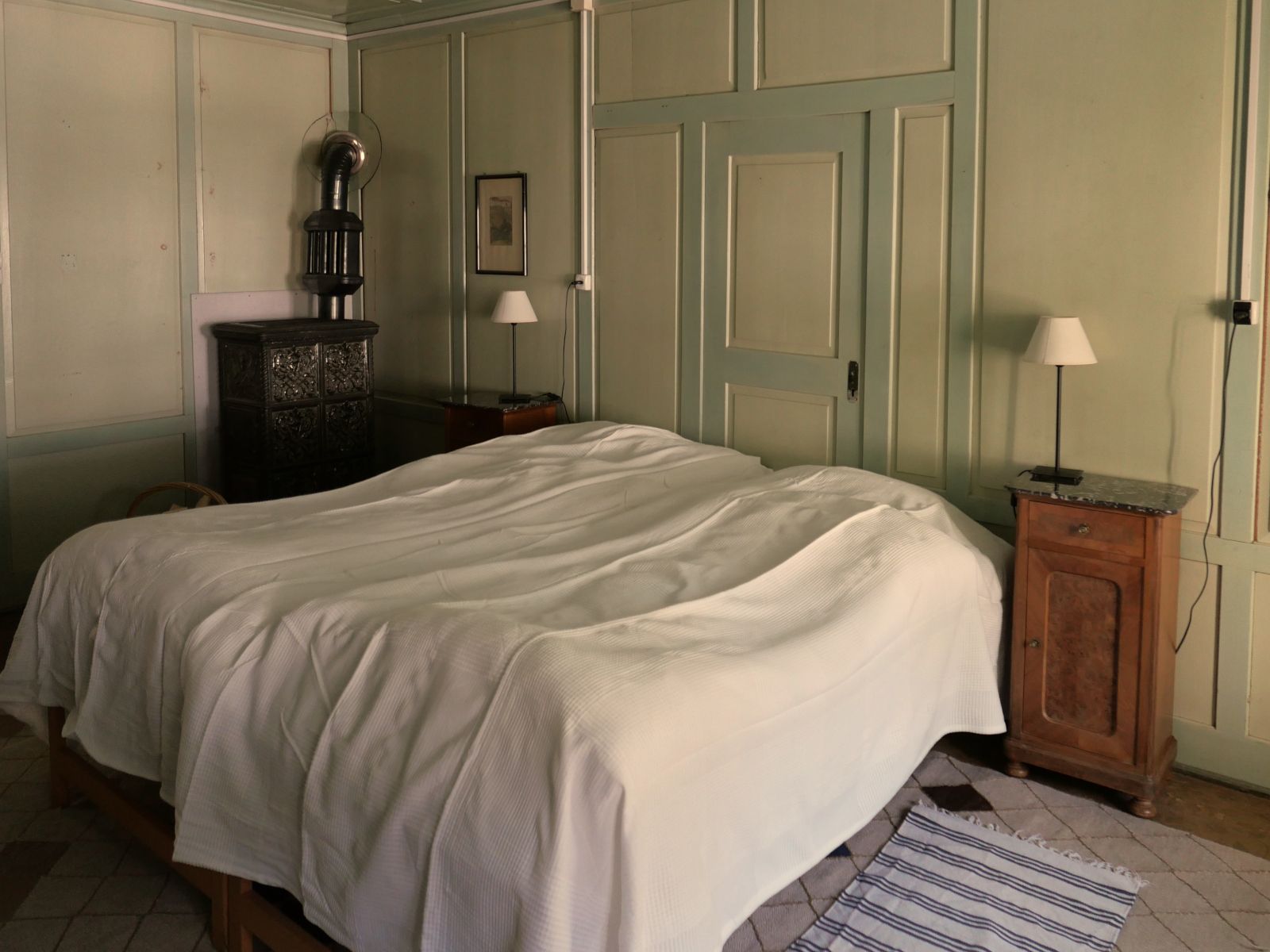 Ein Schlafzimmer mit pastellgrünem Wandtäfer und einem Doppelbett