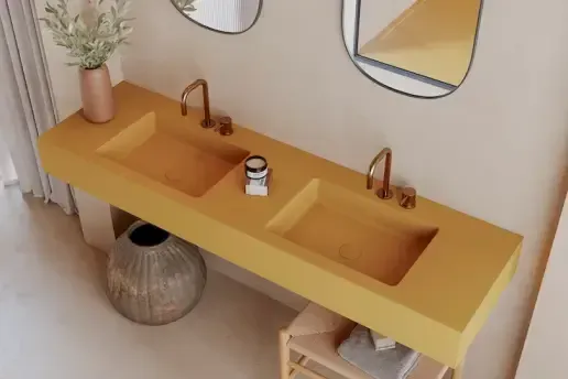 Mueble de baño doble amarillo con grifería y elementos decorativos de bronce.
