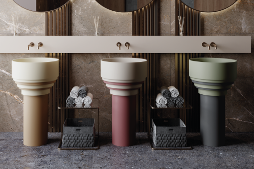 Tres lavabos de pedestal con diferentes combinaciones de colores; toallas y cestas debajo.