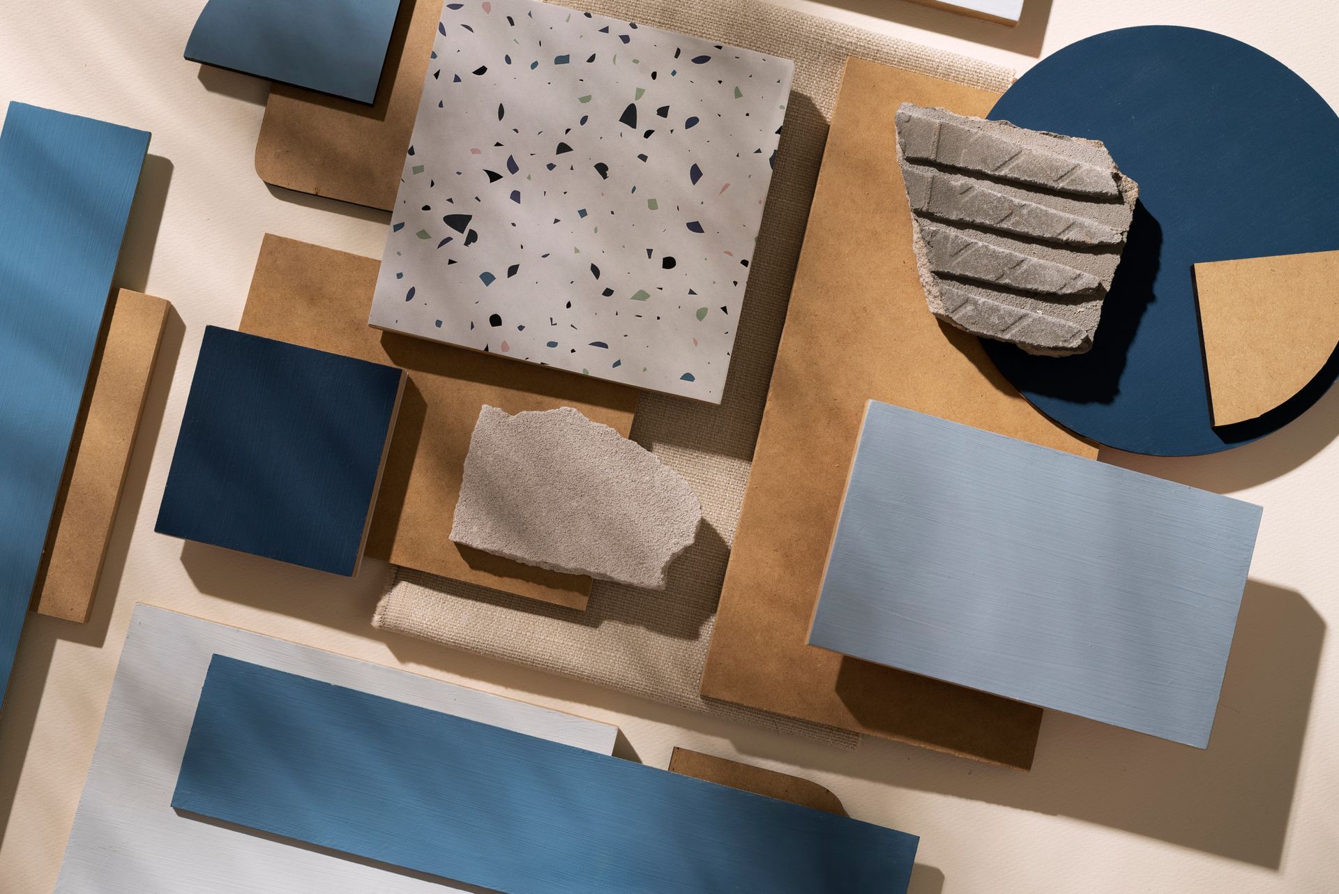 Surtido de muestras de materiales azules, grises y marrones, incluyendo hormigón, madera y cuero