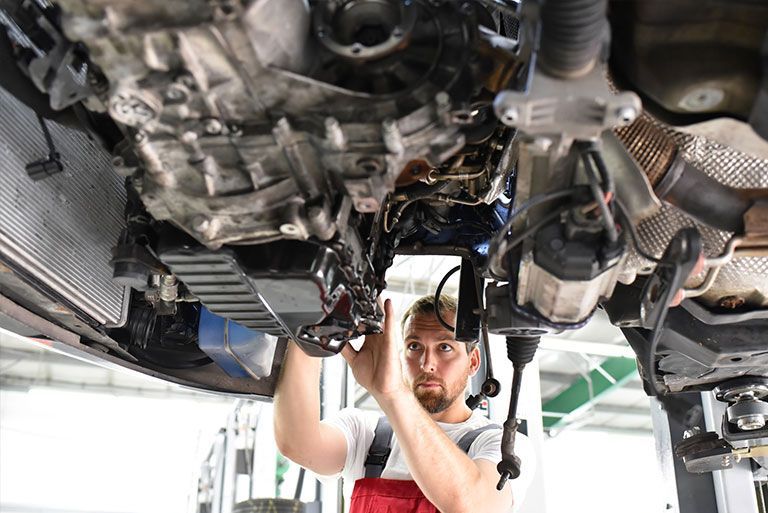 Kohls & Partner GmbH - Kfz-Mechatroniker arbeitet an der Unterseite eines Fahrzeugs