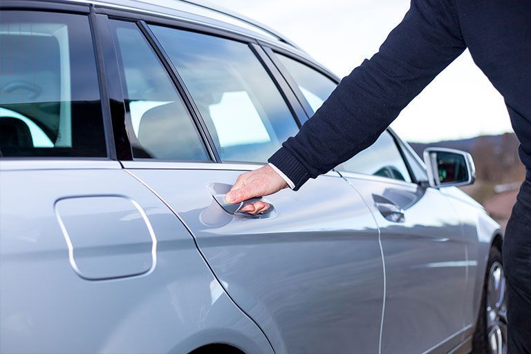 Kohls & Partner GmbH - Mann im Anzug greift nach dem Türgriff einer Hintertür eines Kombis