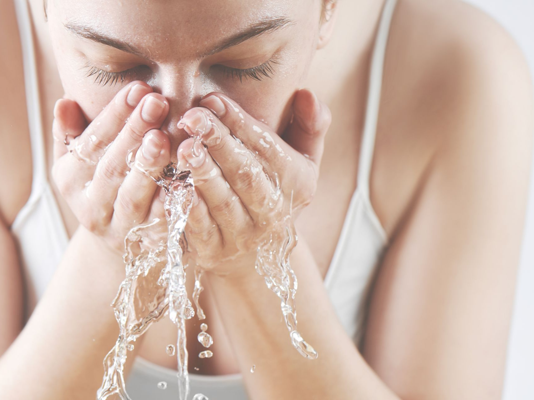 Femme qui se nettoie le visage avec de l'eau.