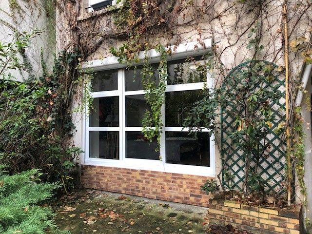 Porte-fenêtre en PVC vue de l'extérieur donnant sur un jardin