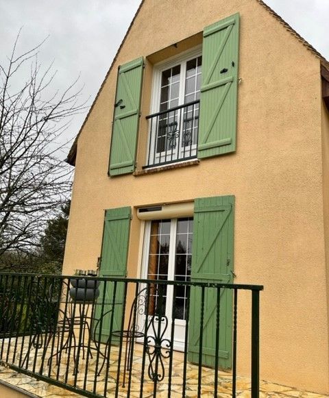 Mur d'une maison avec des grandes fenêtres et volets battant verts