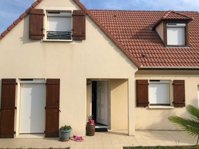 Façade d'une maison avec plusieurs modèles de volets roulants solaires baissés