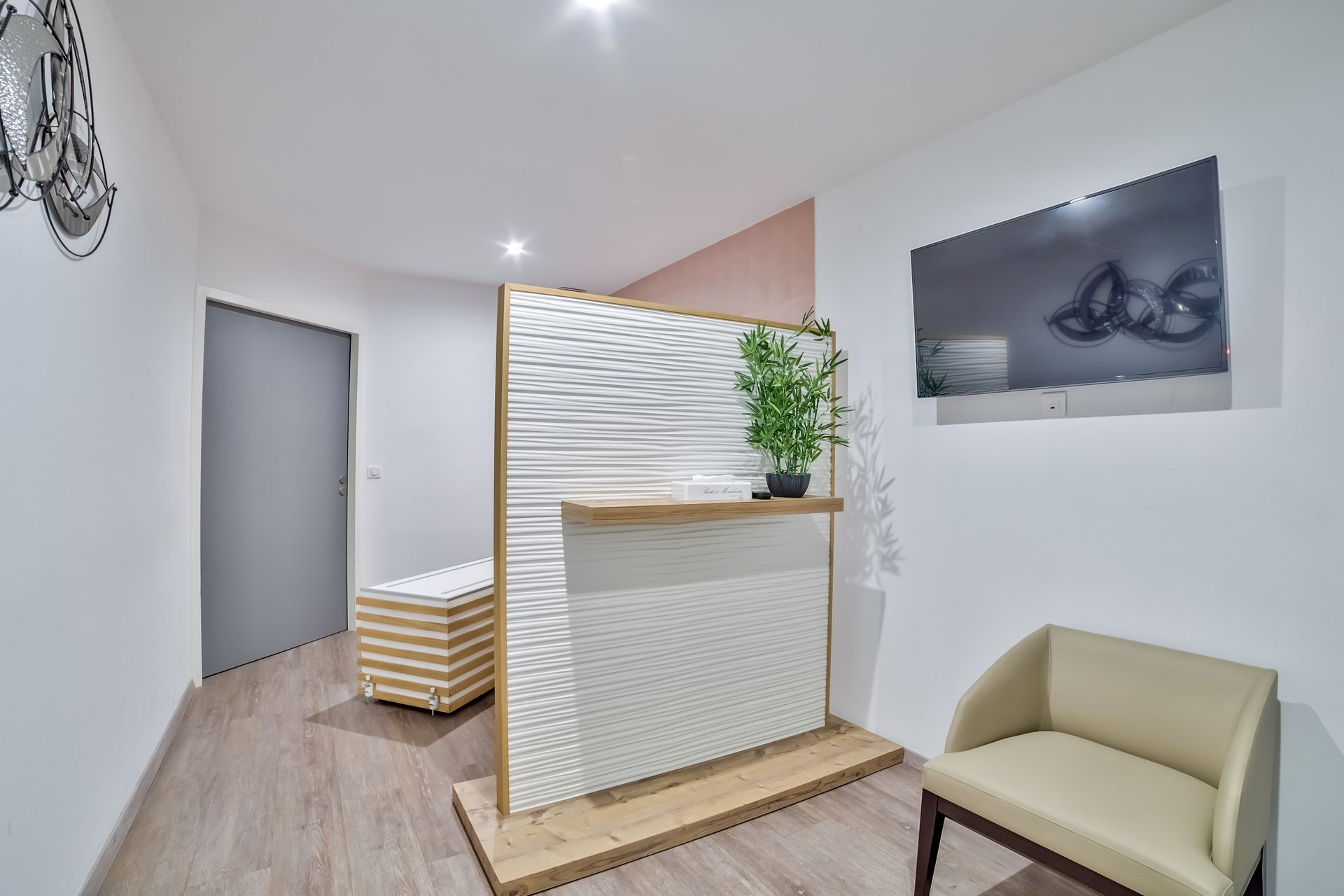 Hall d’entrée moderne de bureau avec comptoir d’accueil, fauteuil beige, œuvres d’art murales et murs blancs texturés