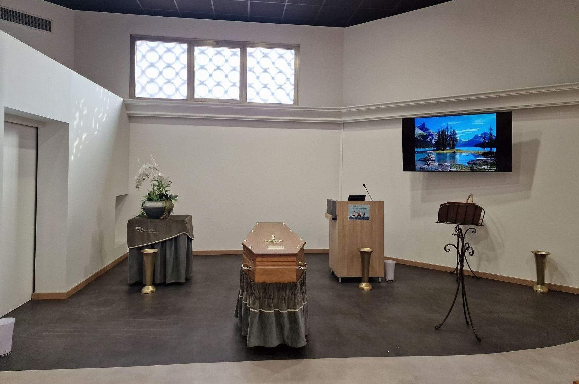 Salle de galerie avec des objets recouverts, un écran de télévision et un trépied sur un sol sombre.