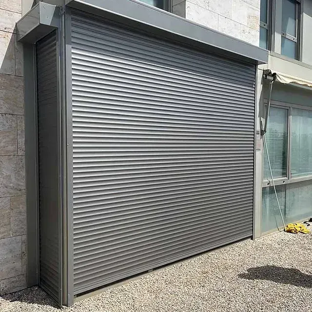 Persiana de seguridad enrollable, gris y cerrada, en el exterior de un edificio.