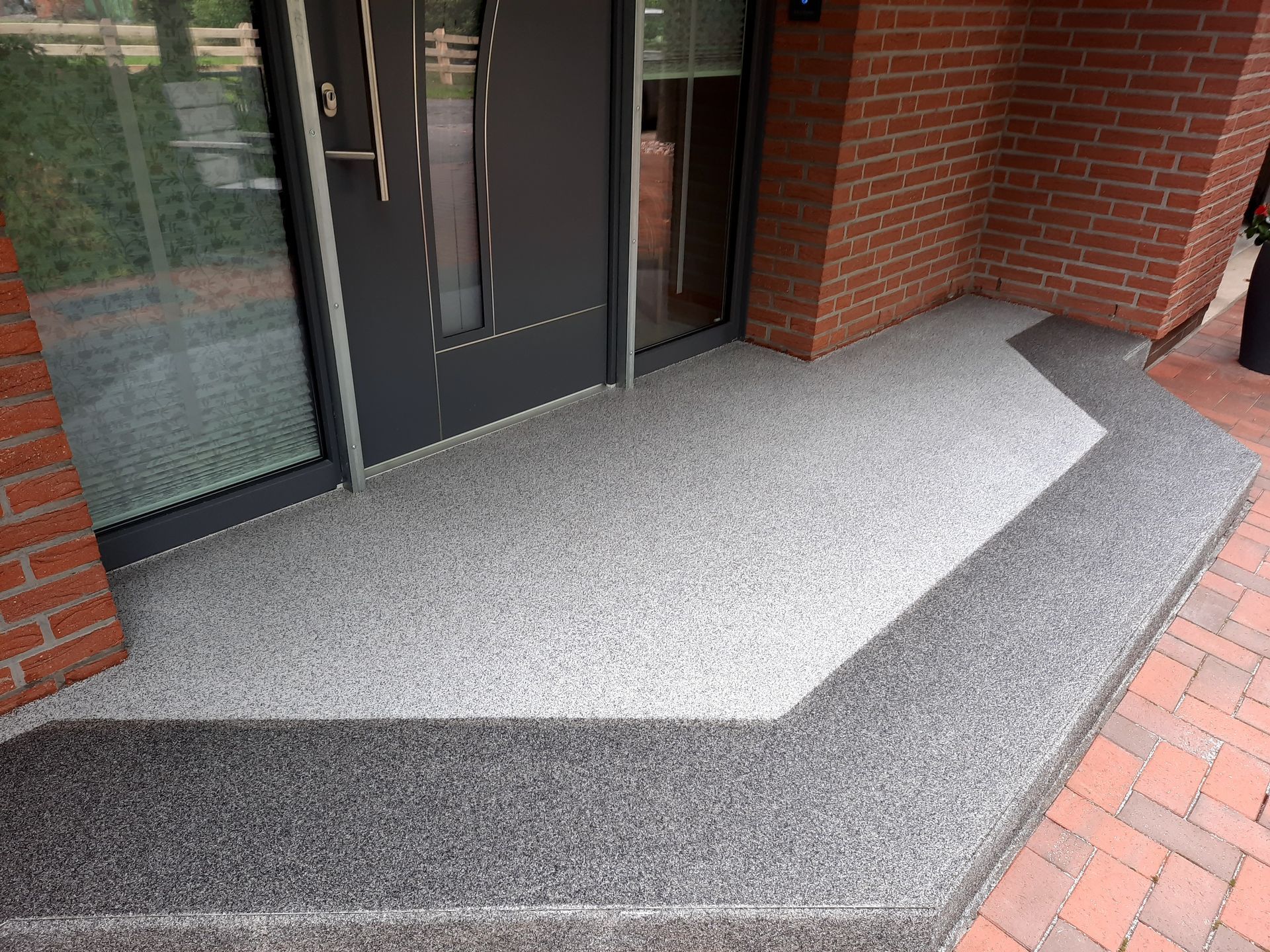 Ein Backsteingebäude mit einer schwarzen Tür und Stufen, die dorthin führen.