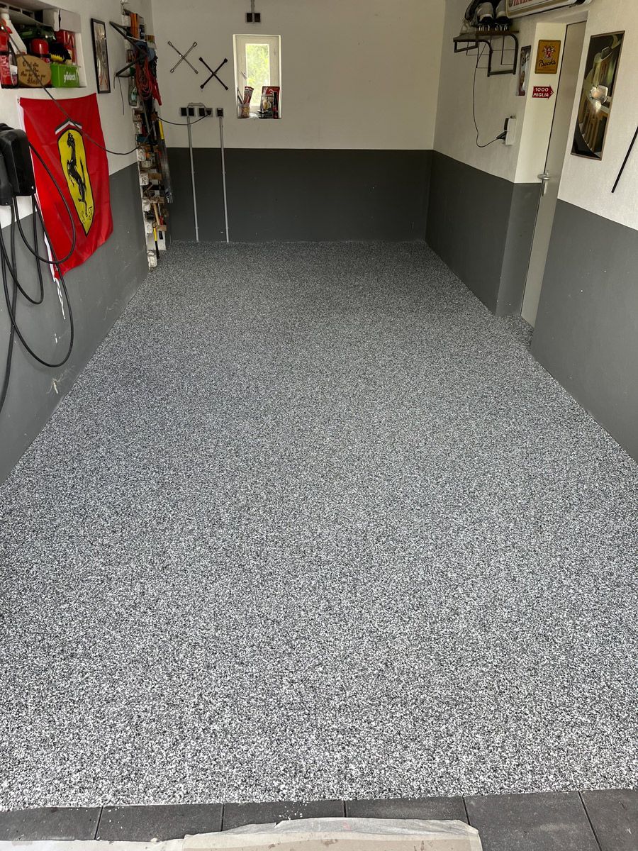 Eine Zimmerecke mit grauem Boden und weißen Wänden.