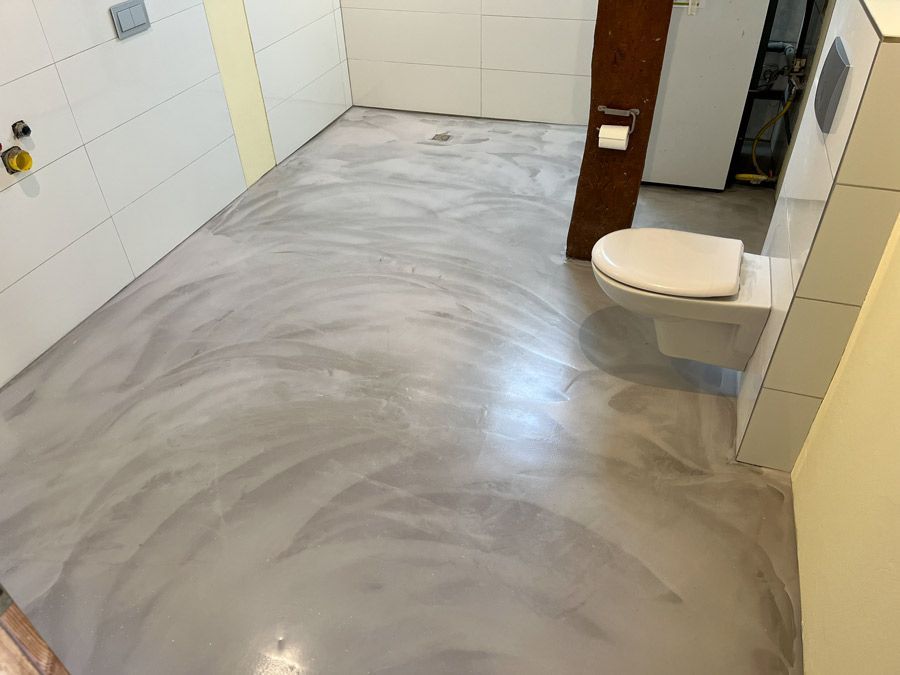 Ein Badezimmer mit Toilette und Betonboden.