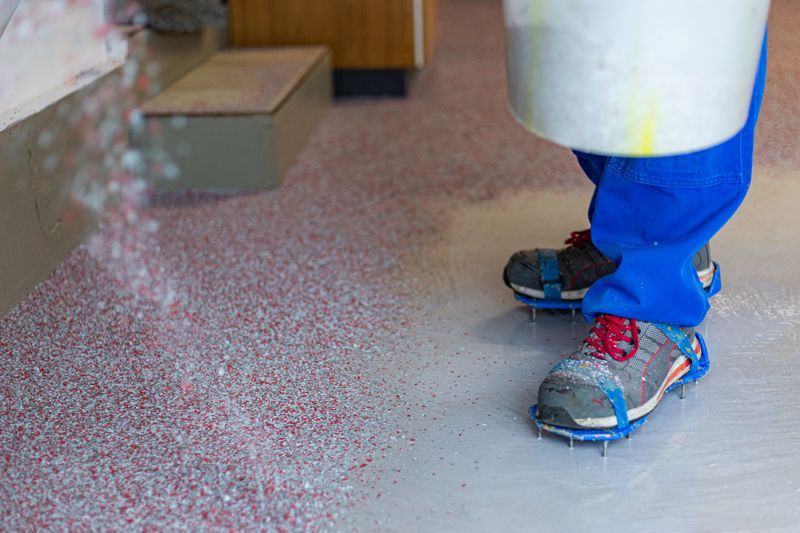 Eine Person mit Schlittschuhen steht auf einem Betonboden.