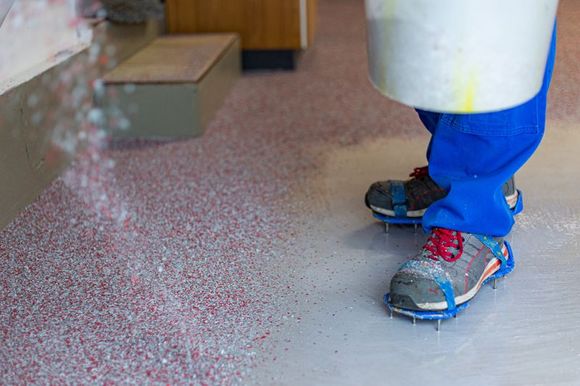 Eine Person mit Schlittschuhen steht auf einem Betonboden.
