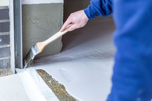Eine Person streicht eine Wand mit einem Pinsel.