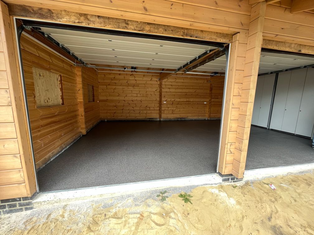 Eine leere Garage mit offenem Tor und Betonboden.