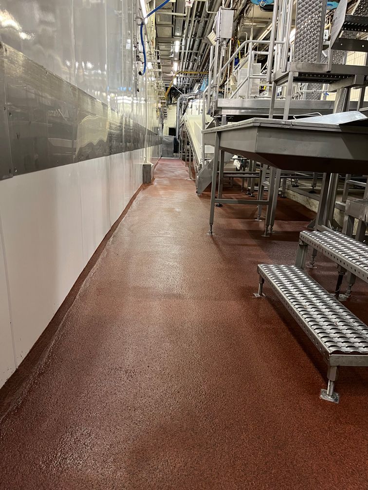 Ein langer Flur in einer Fabrik mit roten Böden und Treppen.