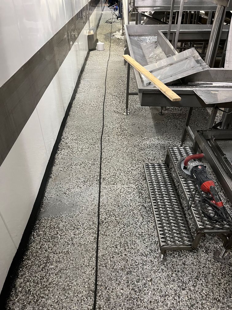 Eine Küche mit vielen Geräten aus Edelstahl und einem Abfluss im Boden.