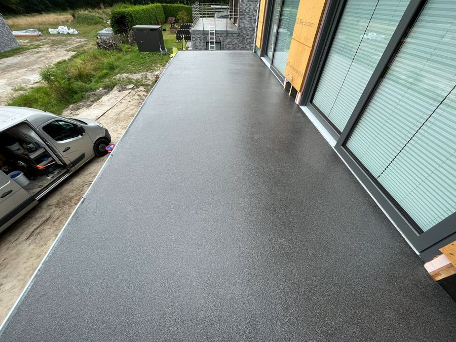 Ein Auto ist an der Seite eines Gebäudes neben einem Balkon geparkt.