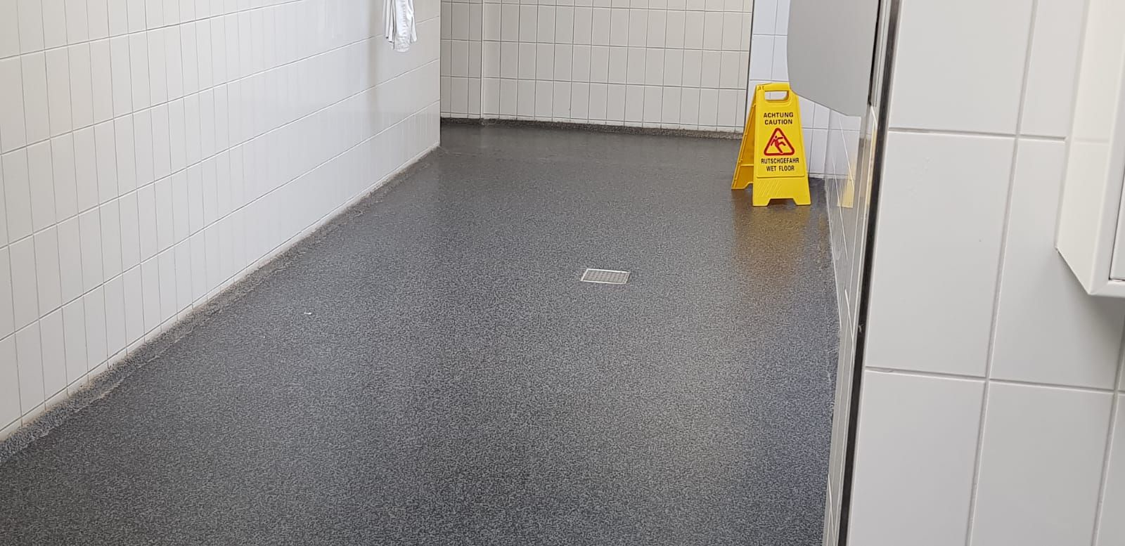 Eine große Küche mit Geräten aus Edelstahl und grauem Boden.