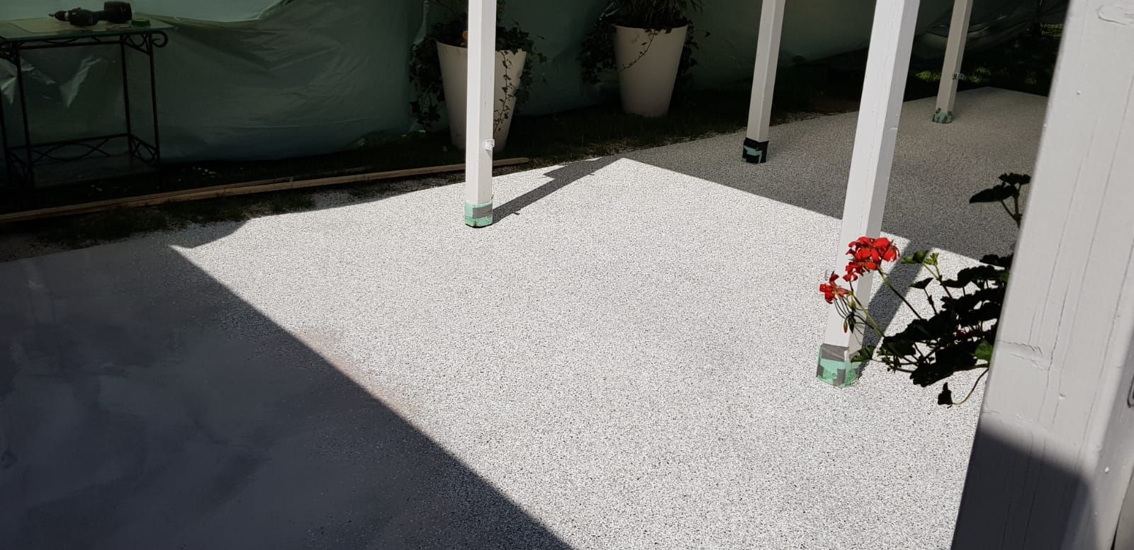 Eine Terrasse mit weißem Kies und Blumen darauf.