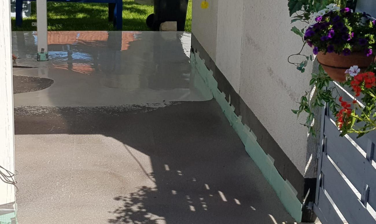 Ein Betonweg neben einem Zaun mit Blumen in Töpfen.