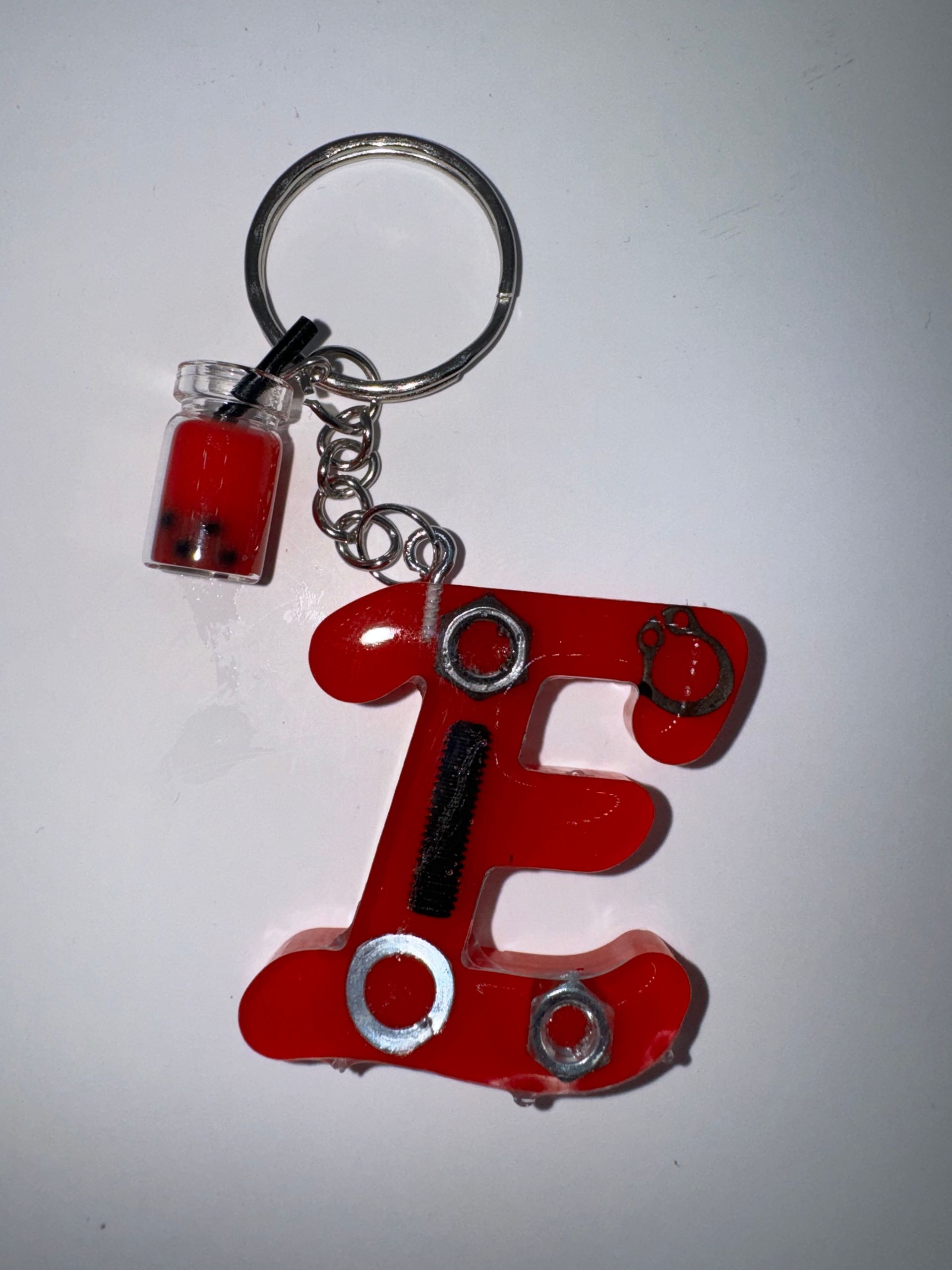 Porte-clés rouge en forme de  E  avec une breloque en forme de bubble tea. Anneau argenté.