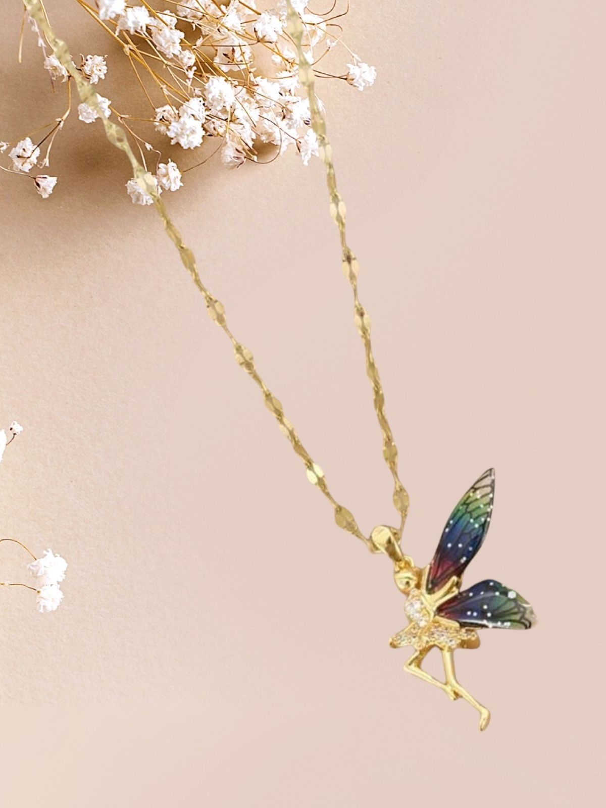 Collier en or avec un pendentif féerique aux ailes colorées, sur fond rose.