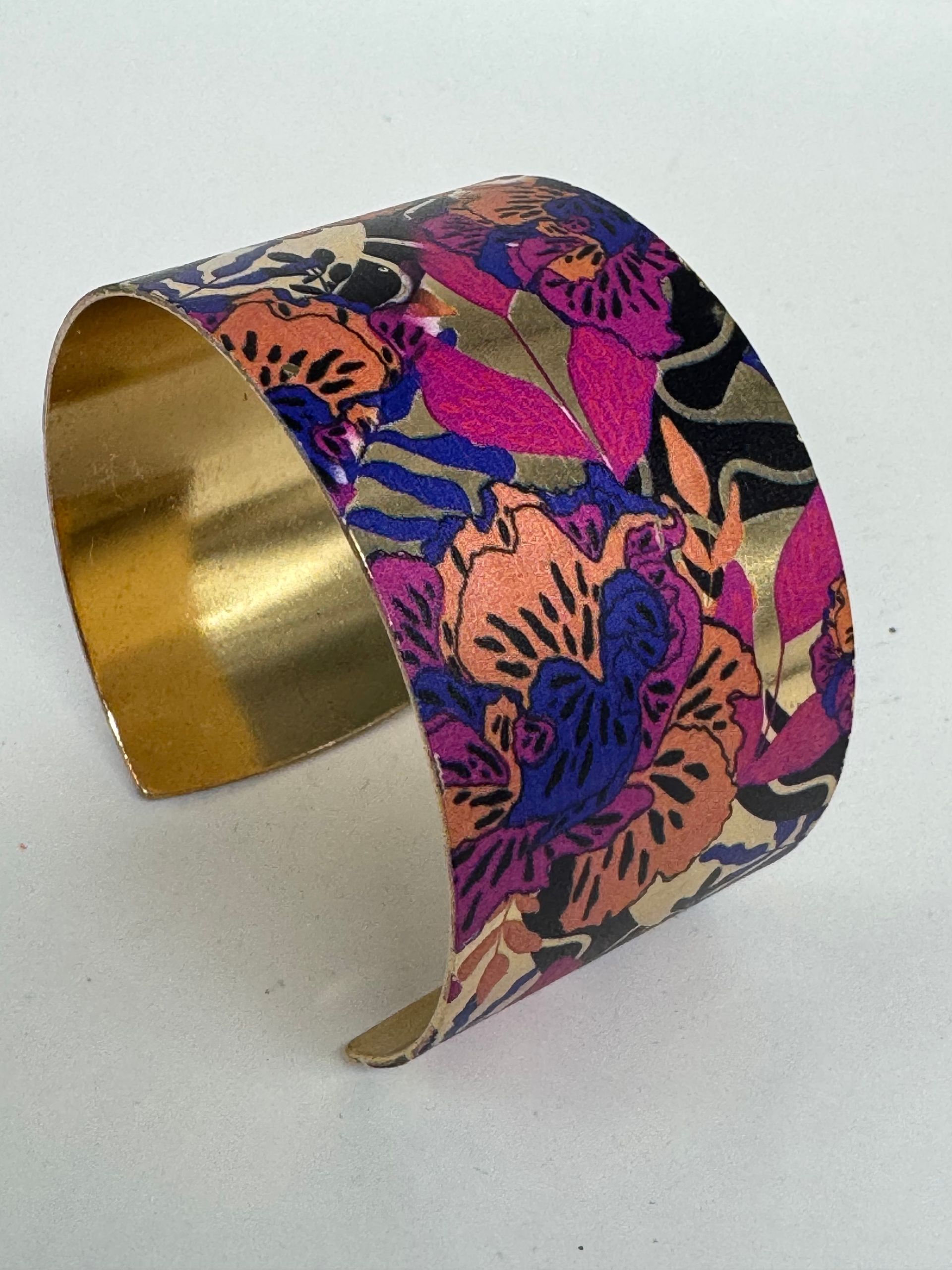 Bracelet manchette large, doublé d'or, orné d'un motif floral coloré rose, orange, bleu et noir.