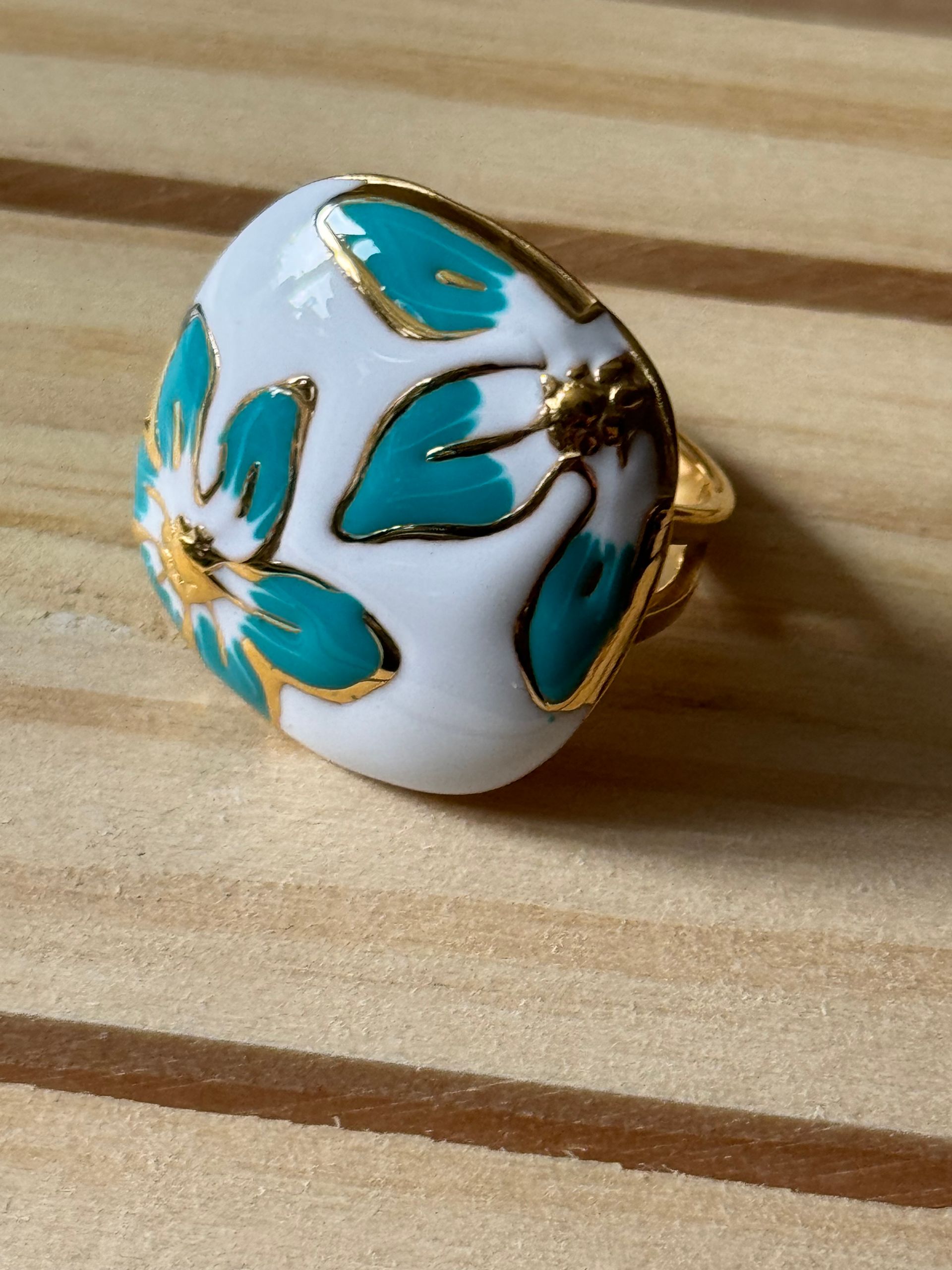 Bague en or avec un dessus émaillé blanc orné d'un motif floral turquoise.