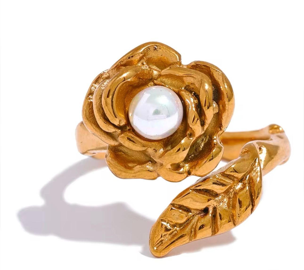 Bague dorée en forme de rose avec une perle au centre et une feuille, sur fond blanc.