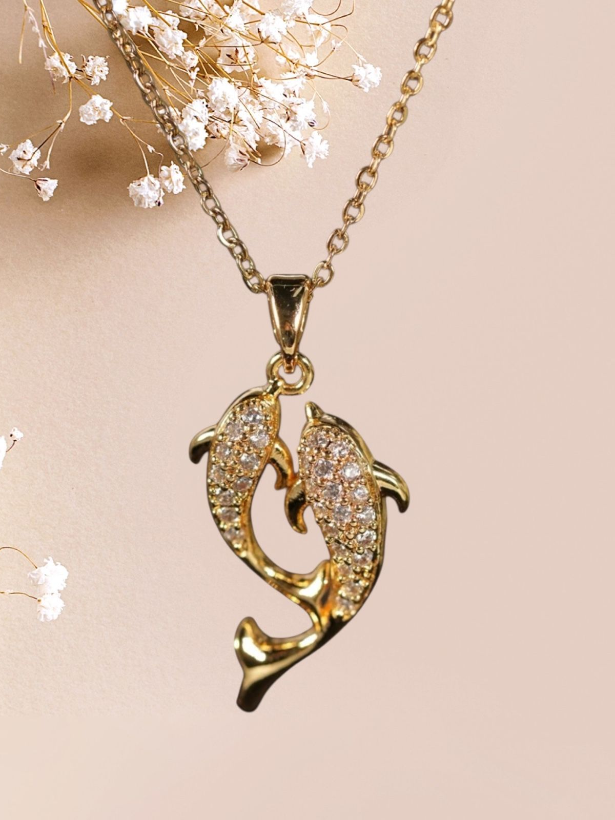 Collier en or avec pendentif deux dauphins, incrusté de cristaux transparents.