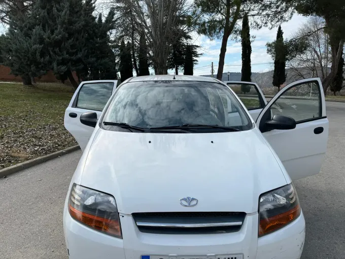Un coche blanco con las puertas abiertas está estacionado al costado de la carretera.