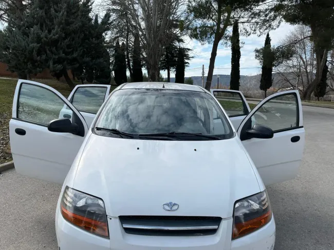 Un coche blanco con las puertas abiertas está estacionado al costado de la carretera.