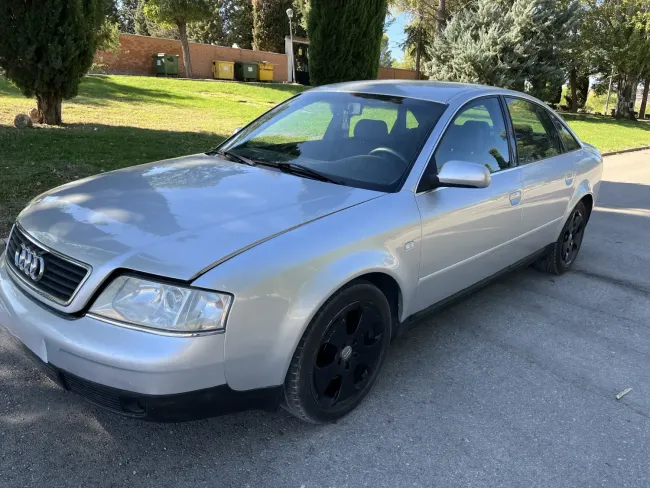 Un Audi A6 plateado está estacionado al costado de la carretera.