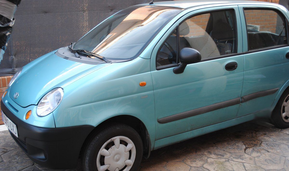 Un pequeño coche azul está aparcado al costado de la carretera.