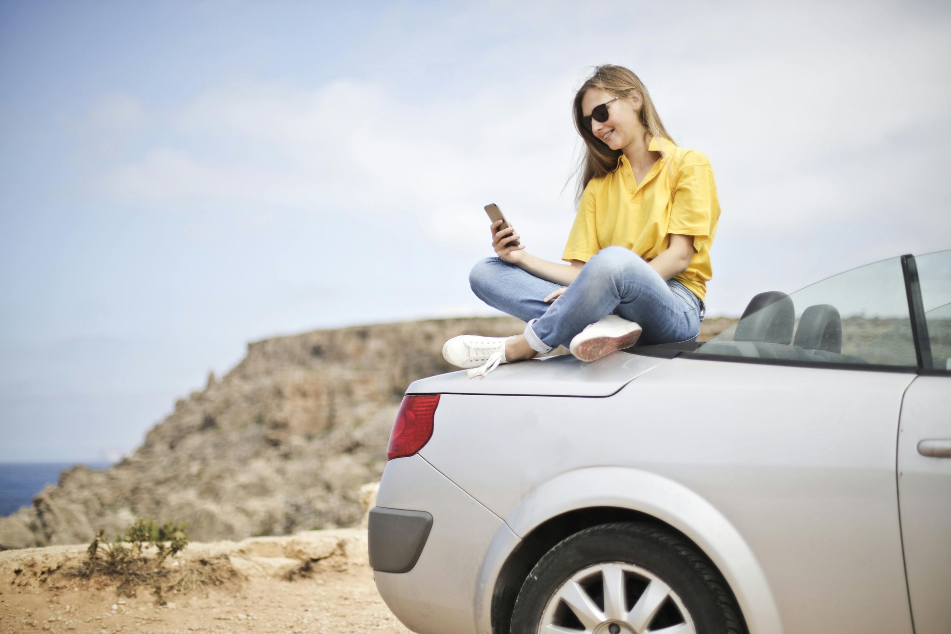 Una mujer está sentada en la parte trasera de un automóvil mirando su teléfono.