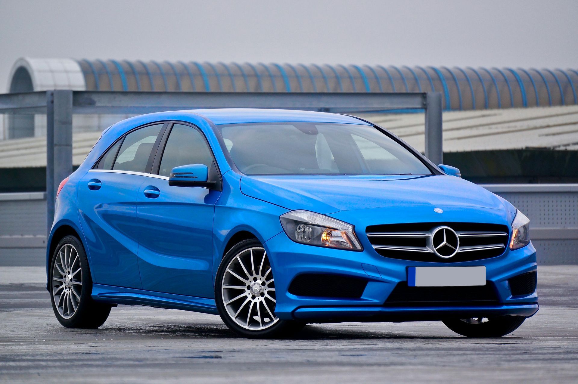 Un Mercedes Benz Clase A hatchback azul está estacionado en un estacionamiento.