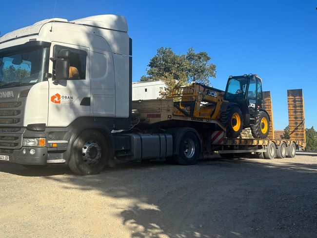Un camión blanco con un tractor amarillo en la parte trasera.