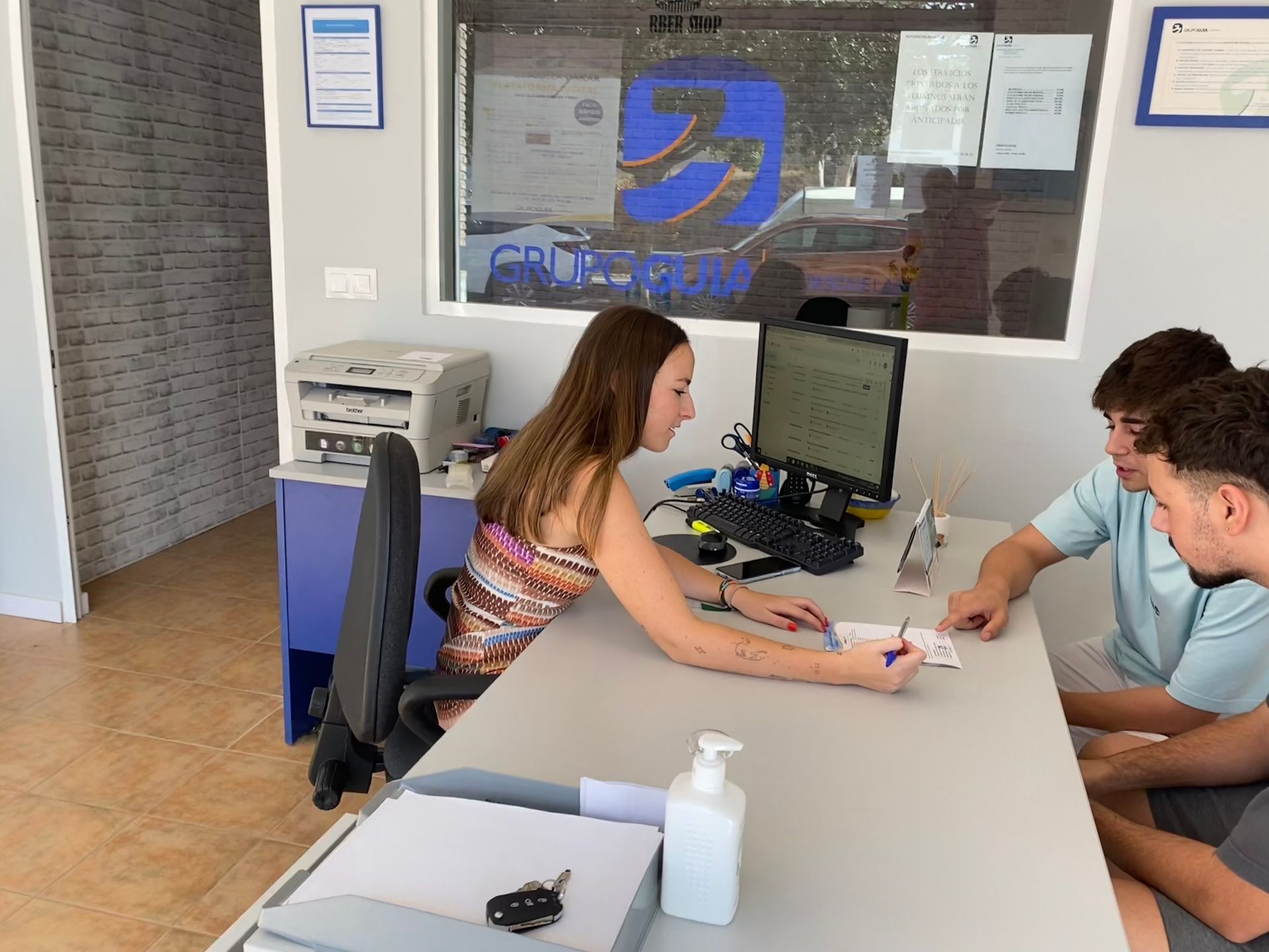 Un grupo de personas está sentada en un escritorio frente a una computadora.