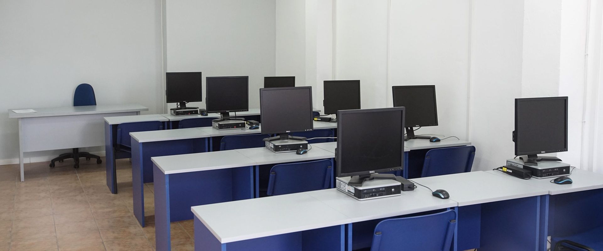 Una fila de escritorios azules con monitores de computadora sobre ellos.